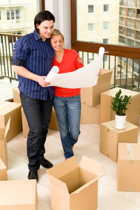 Young couple standing on balcony while planning where unpacked items will be placed.