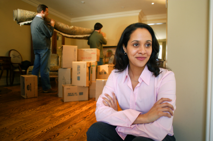Lady smiling with joy while movers cary out items in the background.