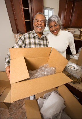 Senior couple packing boxes in kitchen area.